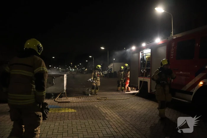 Brandweer blust brandende papiercontainer