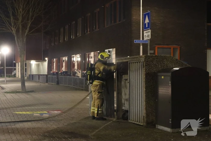 Brandweer blust brandende papiercontainer