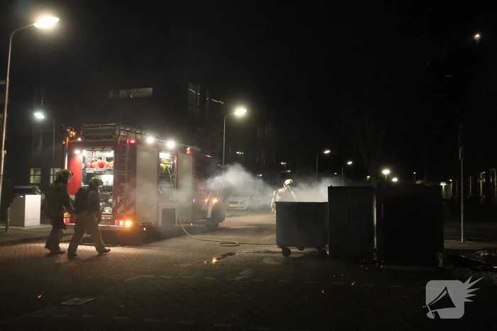 Brandweer blust brandende papiercontainer