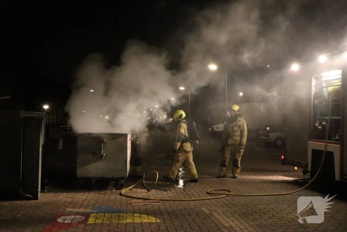 Brandweer blust brandende papiercontainer