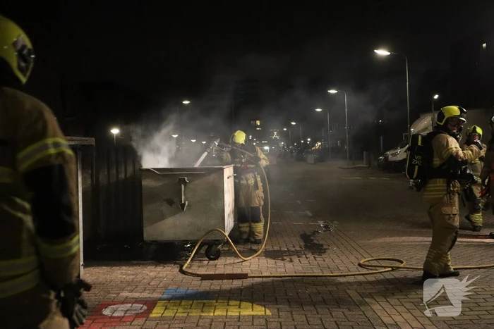 Brandweer blust brandende papiercontainer