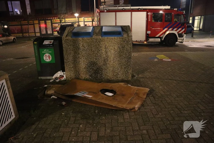 Brandweer blust brandende papiercontainer
