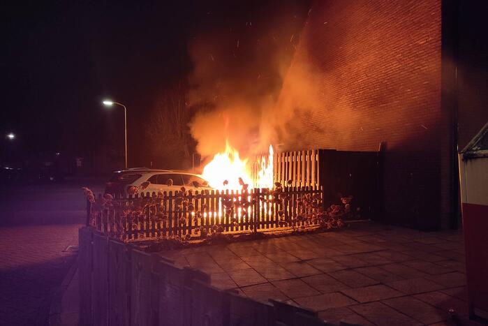 Auto en schutting in brand