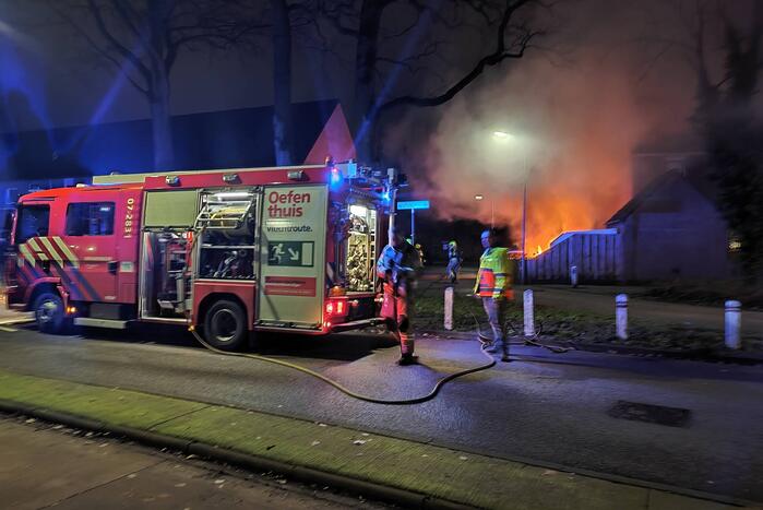 Auto en schutting in brand