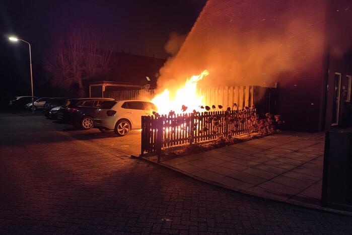 Auto en schutting in brand