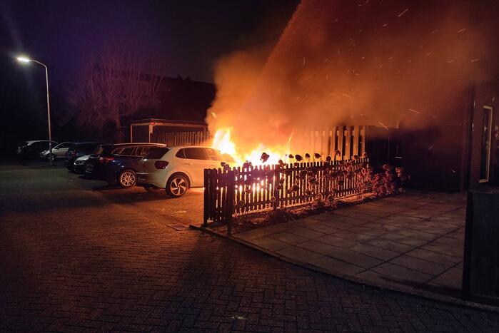 Auto en schutting in brand