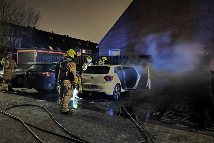 Auto en schutting in brand