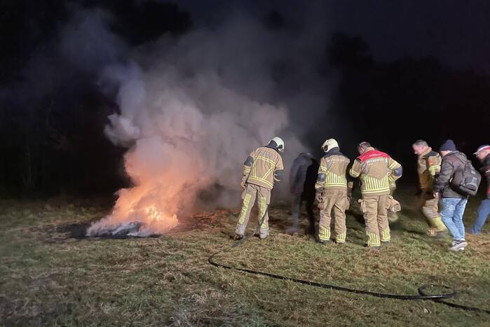 Brandweer blust brandende hoop afval