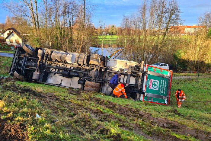 Vrachtwagen belandt op zijn kant onderaan dijk