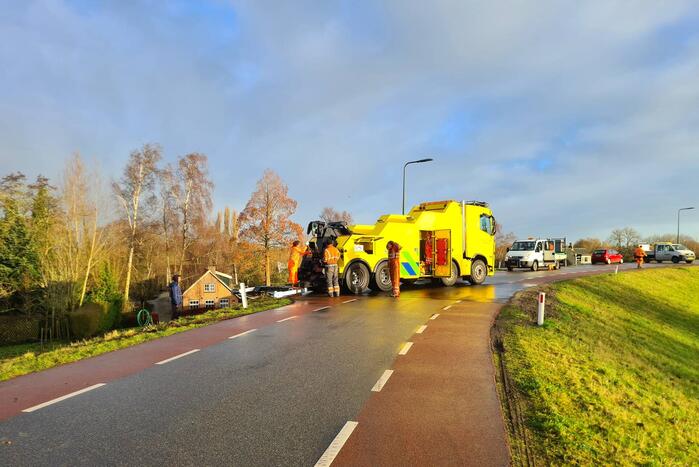 Vrachtwagen belandt op zijn kant onderaan dijk