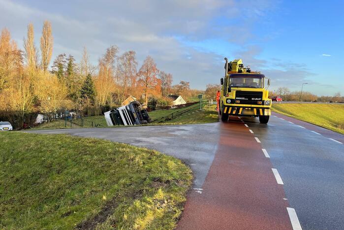 Vrachtwagen belandt op zijn kant onderaan dijk