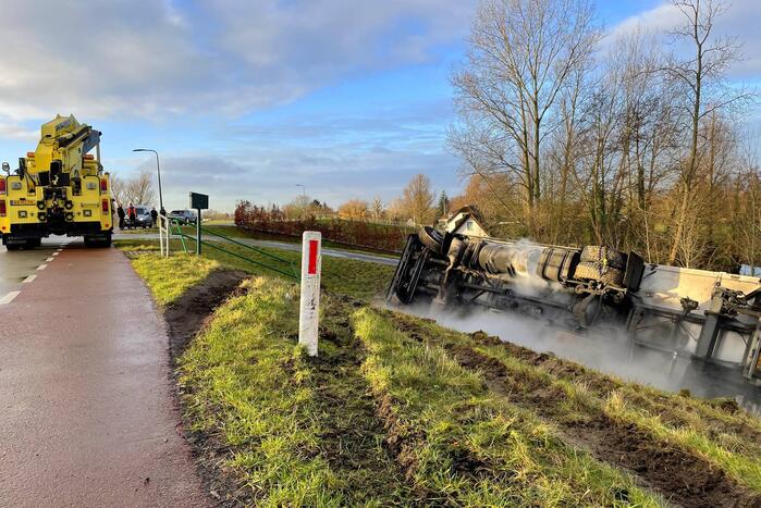 Vrachtwagen belandt op zijn kant onderaan dijk