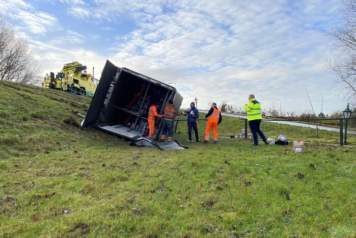 Vrachtwagen belandt op zijn kant onderaan dijk