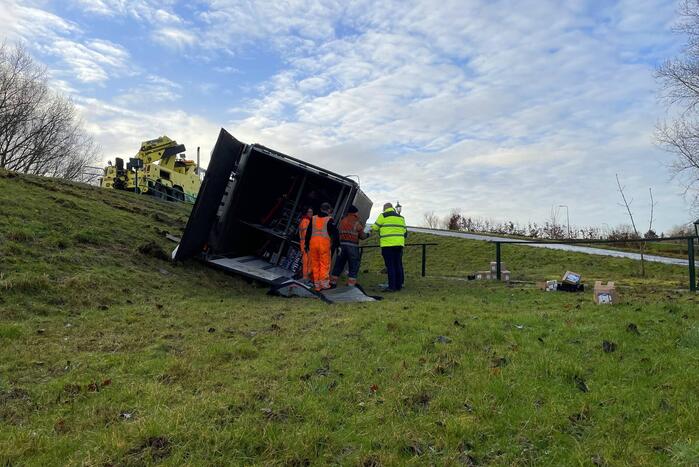 Vrachtwagen belandt op zijn kant onderaan dijk