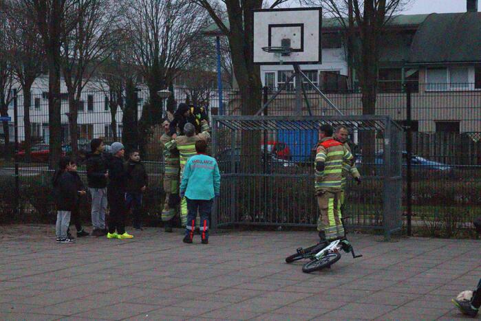 Kind vast met voet tussen spijlen voetbaldoel