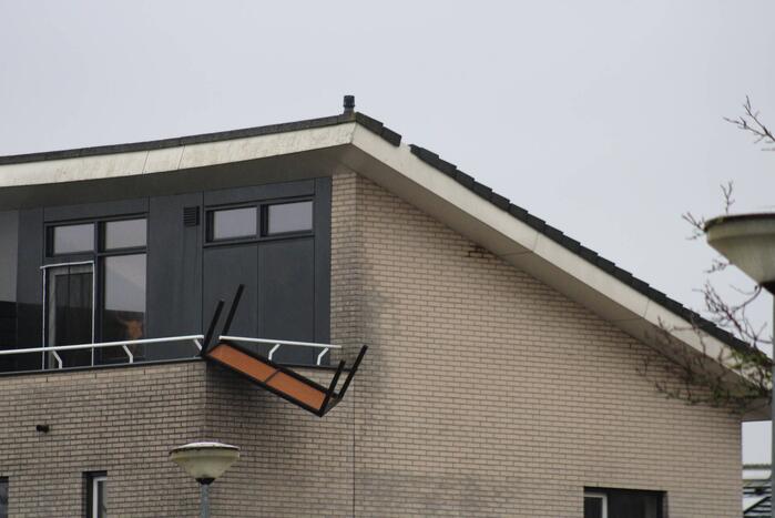 Weggewaaide tafel hangt gevaarlijk over balkonrand