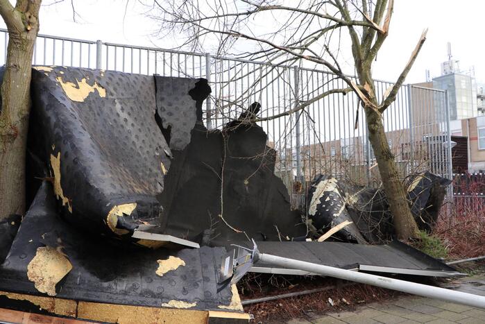 Dakbedekking van flat waait over auto's en lantaarnpalen