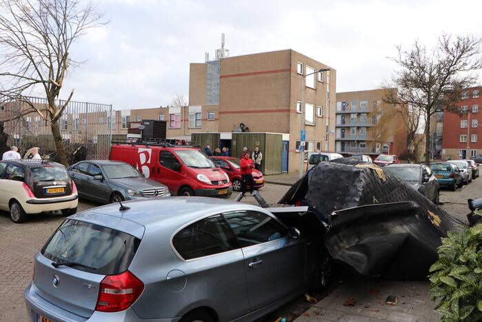Dakbedekking van flat waait over auto's en lantaarnpalen