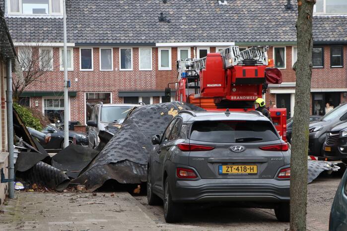 Dakbedekking van flat waait over auto's en lantaarnpalen