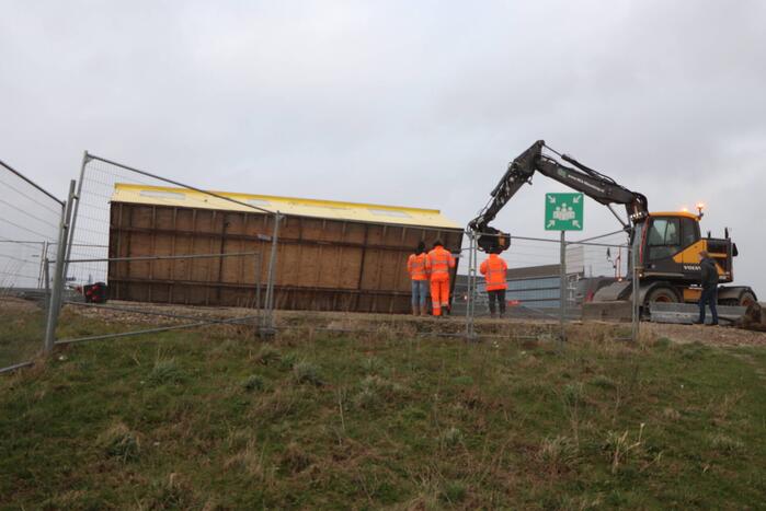 Bouwkeet waait om en belandt op wegdek