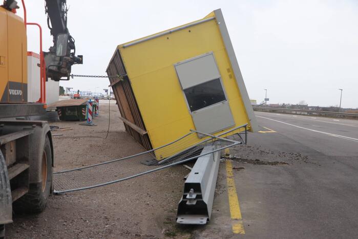 Bouwkeet waait om en belandt op wegdek