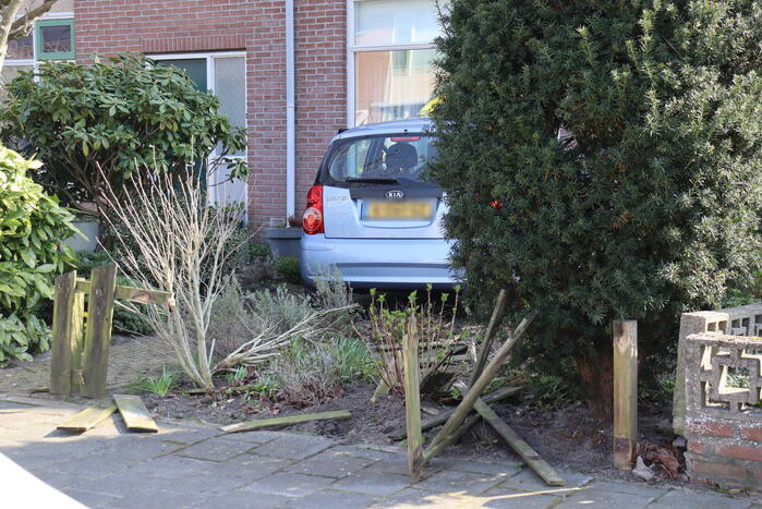 Auto rijdt voortuin van huis binnen