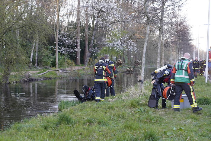 Driewieler aan waterkant, duikers zoeken naar slachtoffer