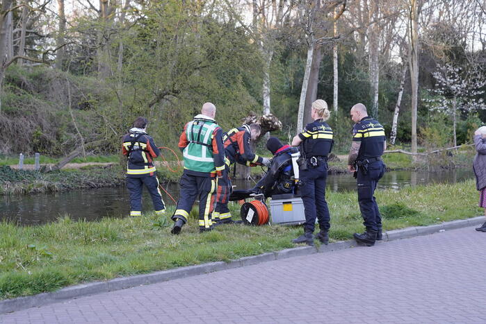 Driewieler aan waterkant, duikers zoeken naar slachtoffer