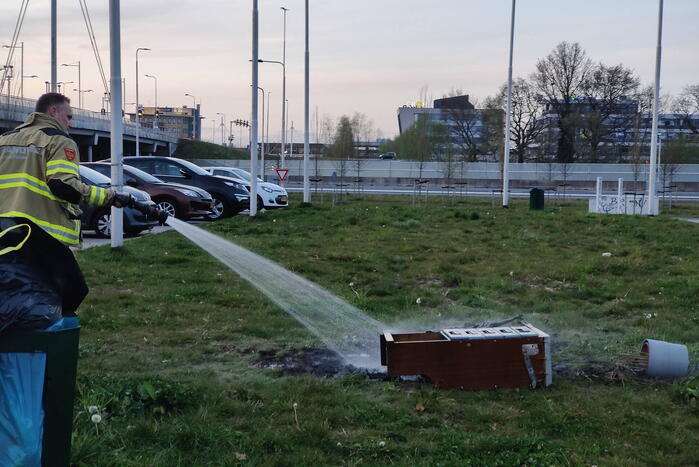 Brandweer blust brandende afvalcontainer