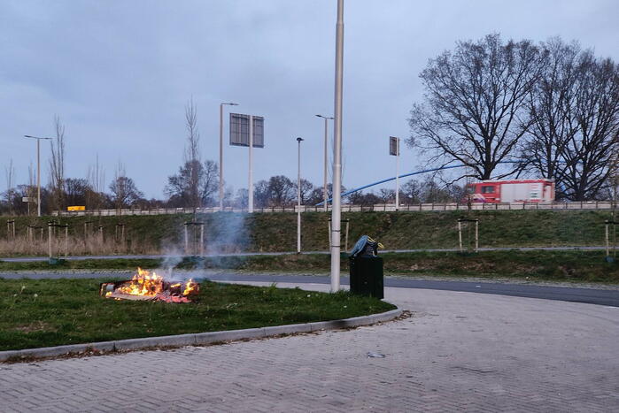 Brandweer blust brandende afvalcontainer