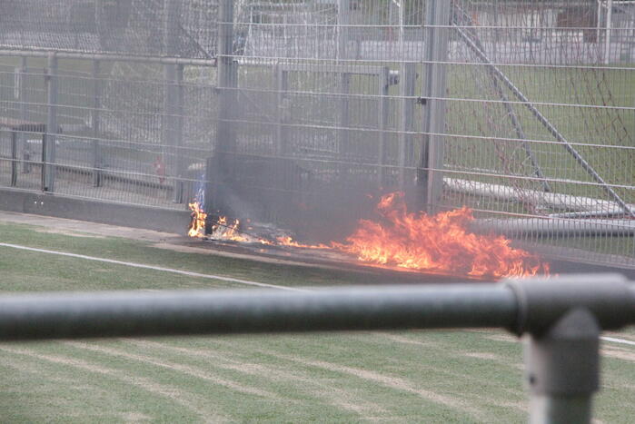 Vlammen bij brand naast sportveld
