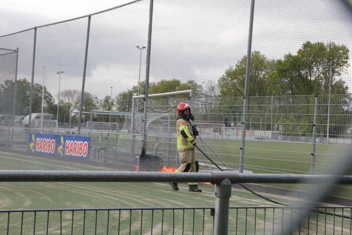 Vlammen bij brand naast sportveld