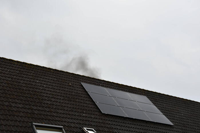 Veel rook uit zolderraam bij brand in woning