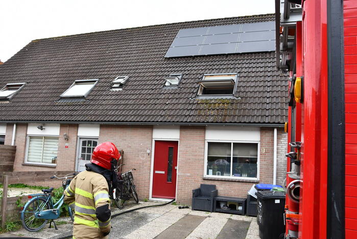 Veel rook uit zolderraam bij brand in woning