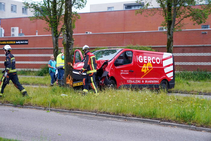 Bestuurder bestelbus bekneld na botsing tegen boom