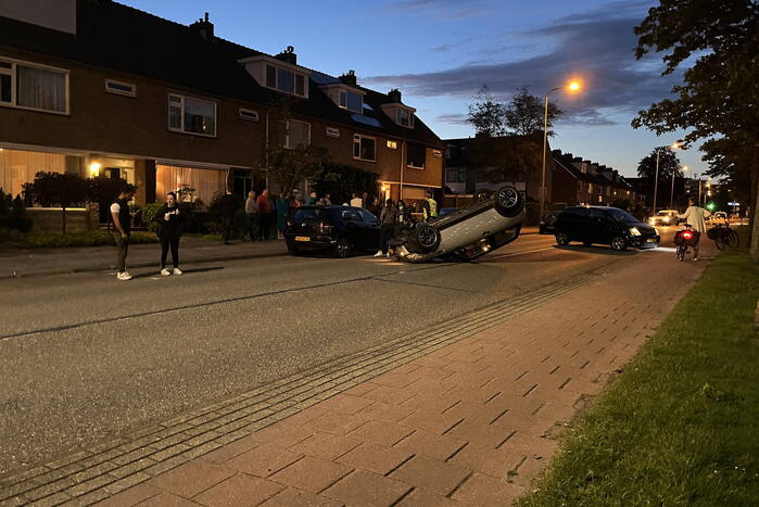 Auto op zijn kop na botsing met geparkeerde auto