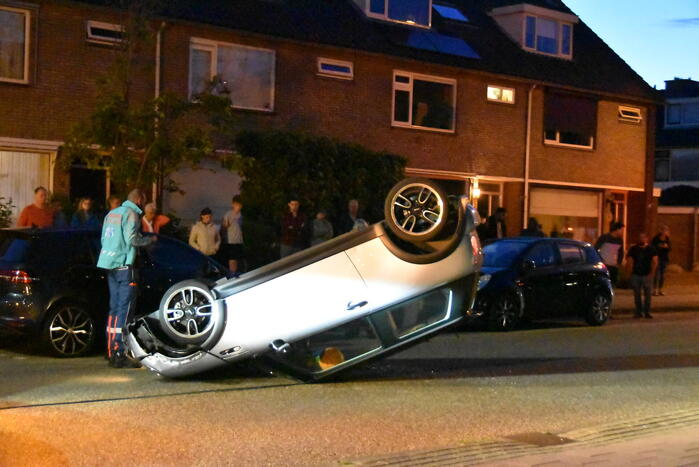 Auto op zijn kop na botsing met geparkeerde auto