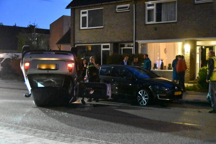 Auto op zijn kop na botsing met geparkeerde auto