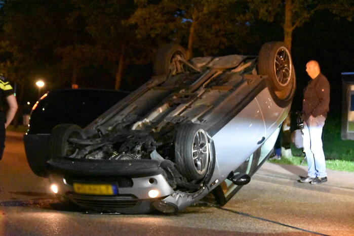 Auto op zijn kop na botsing met geparkeerde auto