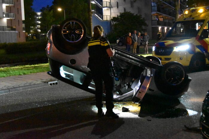 Auto op zijn kop na botsing met geparkeerde auto