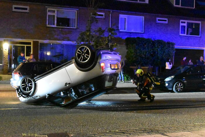 Auto op zijn kop na botsing met geparkeerde auto