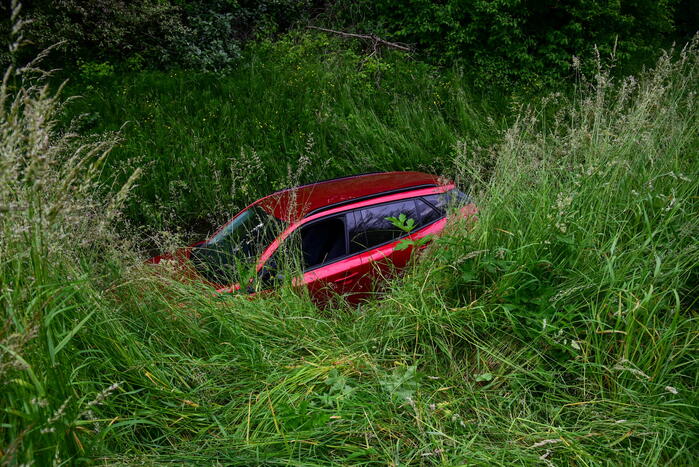 Auto rijdt over rotonde de sloot in