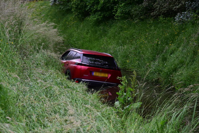 Auto rijdt over rotonde de sloot in