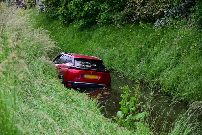 Auto rijdt over rotonde de sloot in
