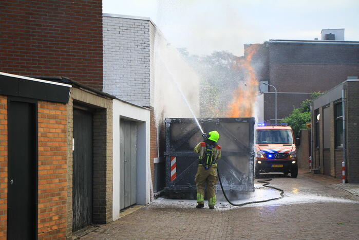 Vlammen slaan uit bouwcontainer met afval