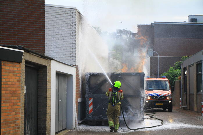 Vlammen slaan uit bouwcontainer met afval