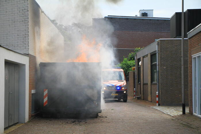 Vlammen slaan uit bouwcontainer met afval