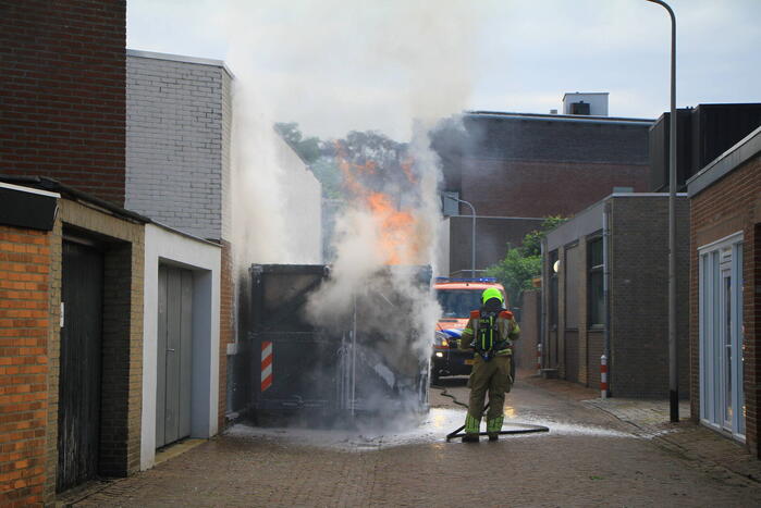 Vlammen slaan uit bouwcontainer met afval