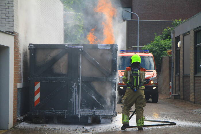 Vlammen slaan uit bouwcontainer met afval