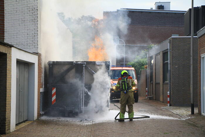 Vlammen slaan uit bouwcontainer met afval